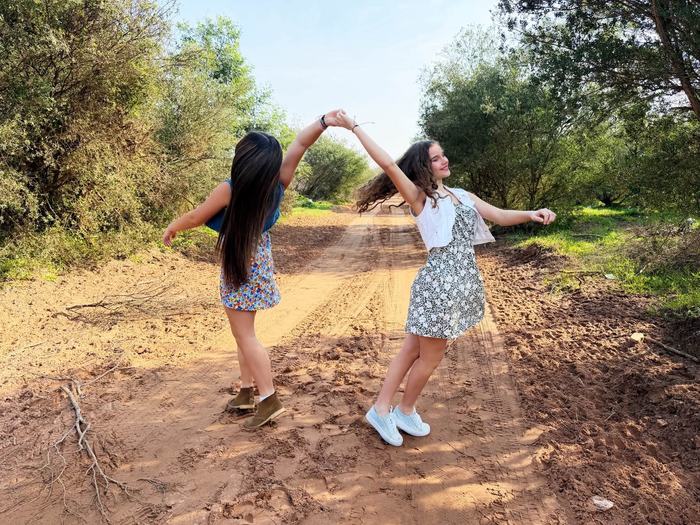 Two friends dancing on a sand road