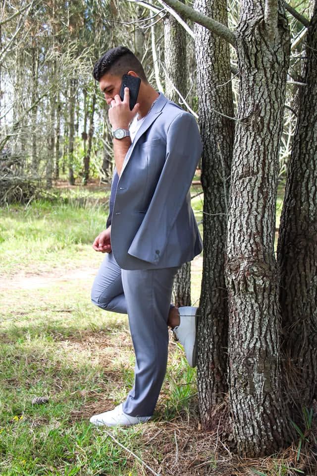 Matric portrait in a grey suit among pine trees